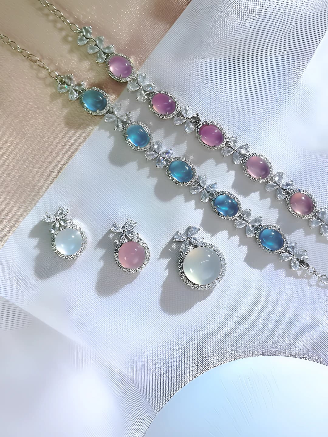Women's jewelry set: necklace with natural white chalcedony and pink crystal, bracelet with natural blue crystal, bow design
